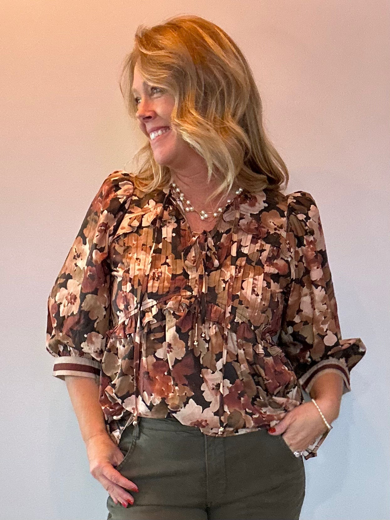 Woman wearing a floral print peplum blouse with a tie front closure and three-quarter sleeves