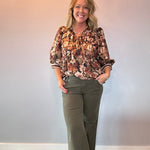 Close-up of the pintuck detail and ruffle trim at the chest of the floral blouse