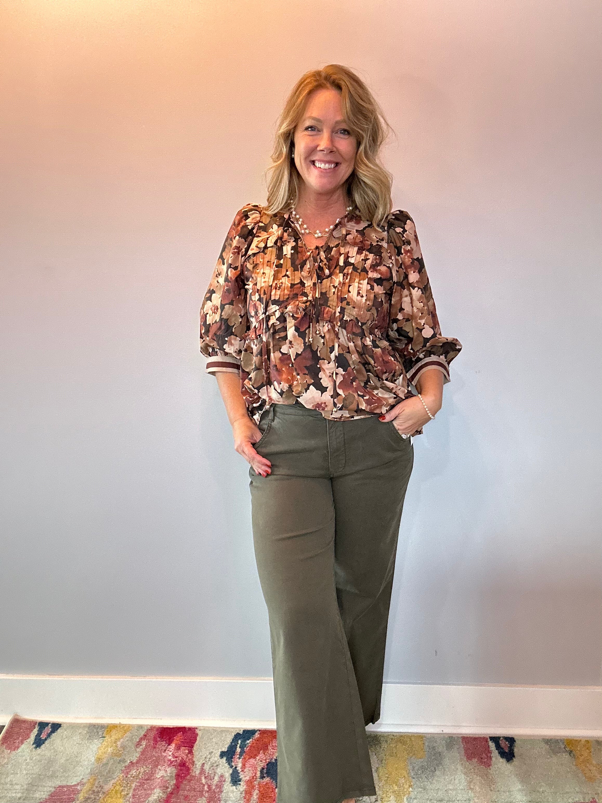 Close-up of the pintuck detail and ruffle trim at the chest of the floral blouse