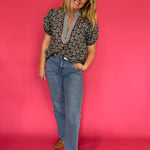 Side view of the deep green printed top worn tucked into high waisted denim for fall days