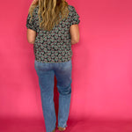 Three quarter view of the dark green printed woven top styled with tailored trousers for work