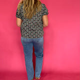 Three quarter view of the dark green printed woven top styled with tailored trousers for work
