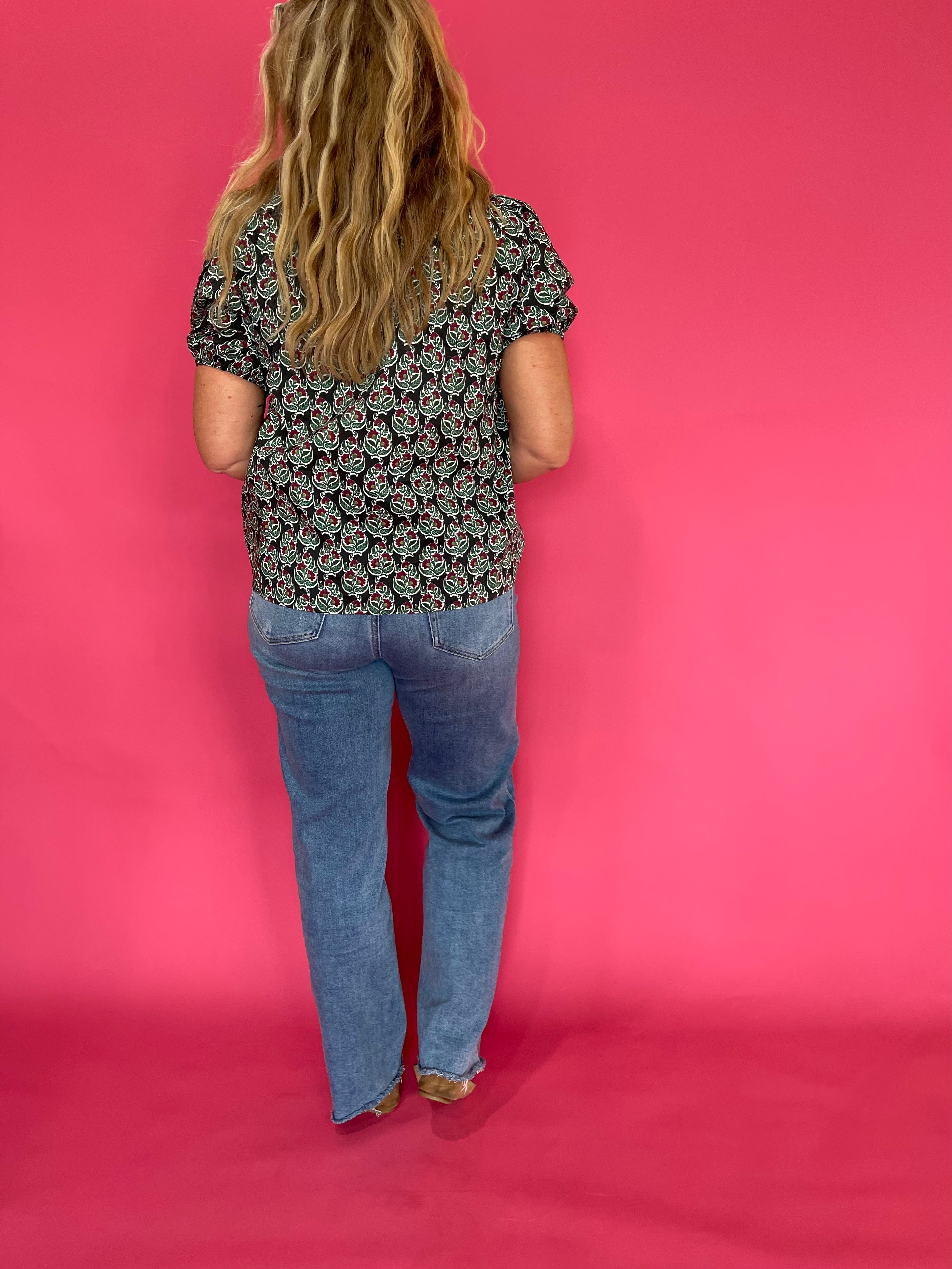 Three quarter view of the dark green printed woven top styled with tailored trousers for work