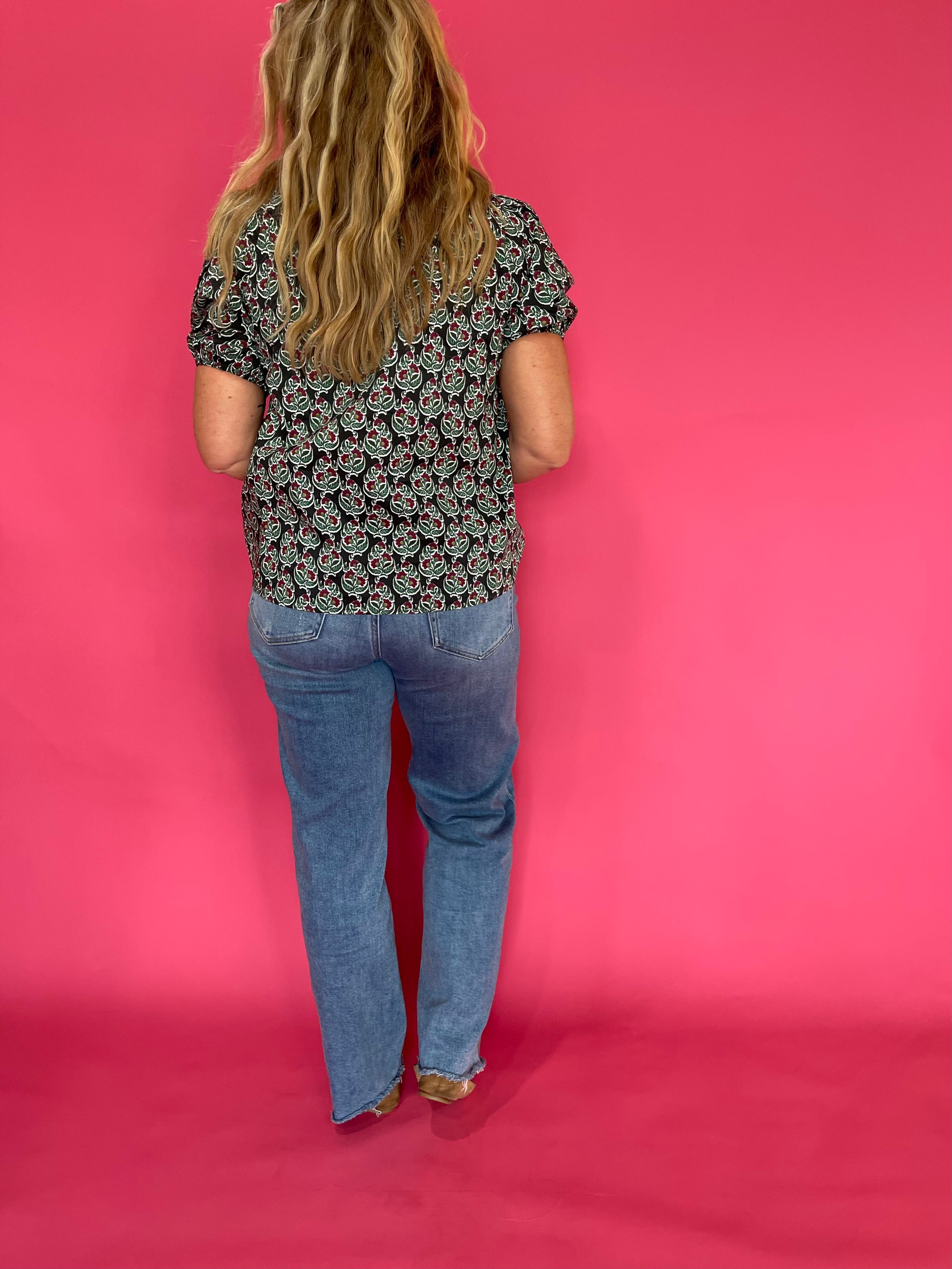 Three quarter view of the dark green printed woven top styled with tailored trousers for work