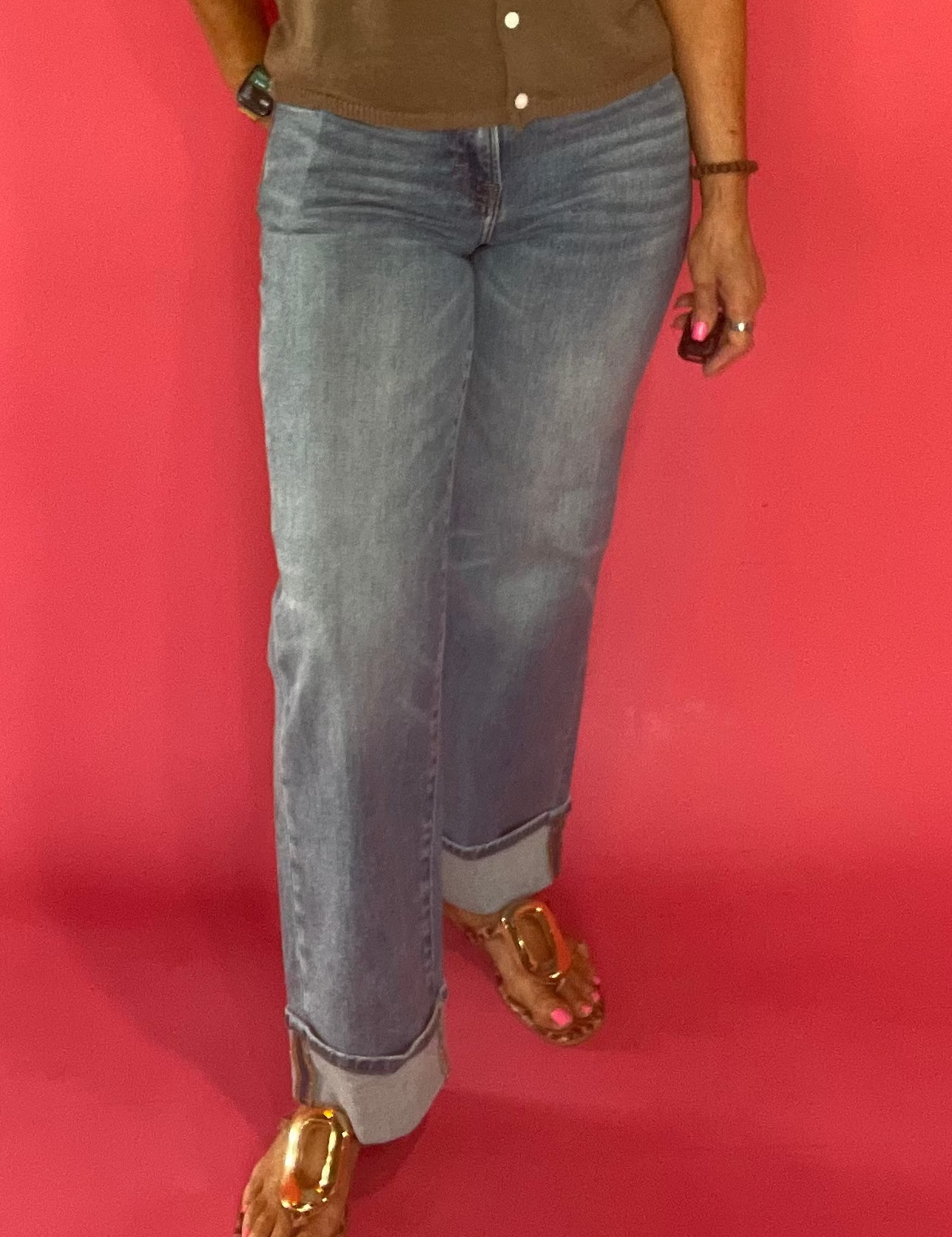 Woman wearing mid rise medium wash cuffed dad jeans with a tucked tee and sneakers