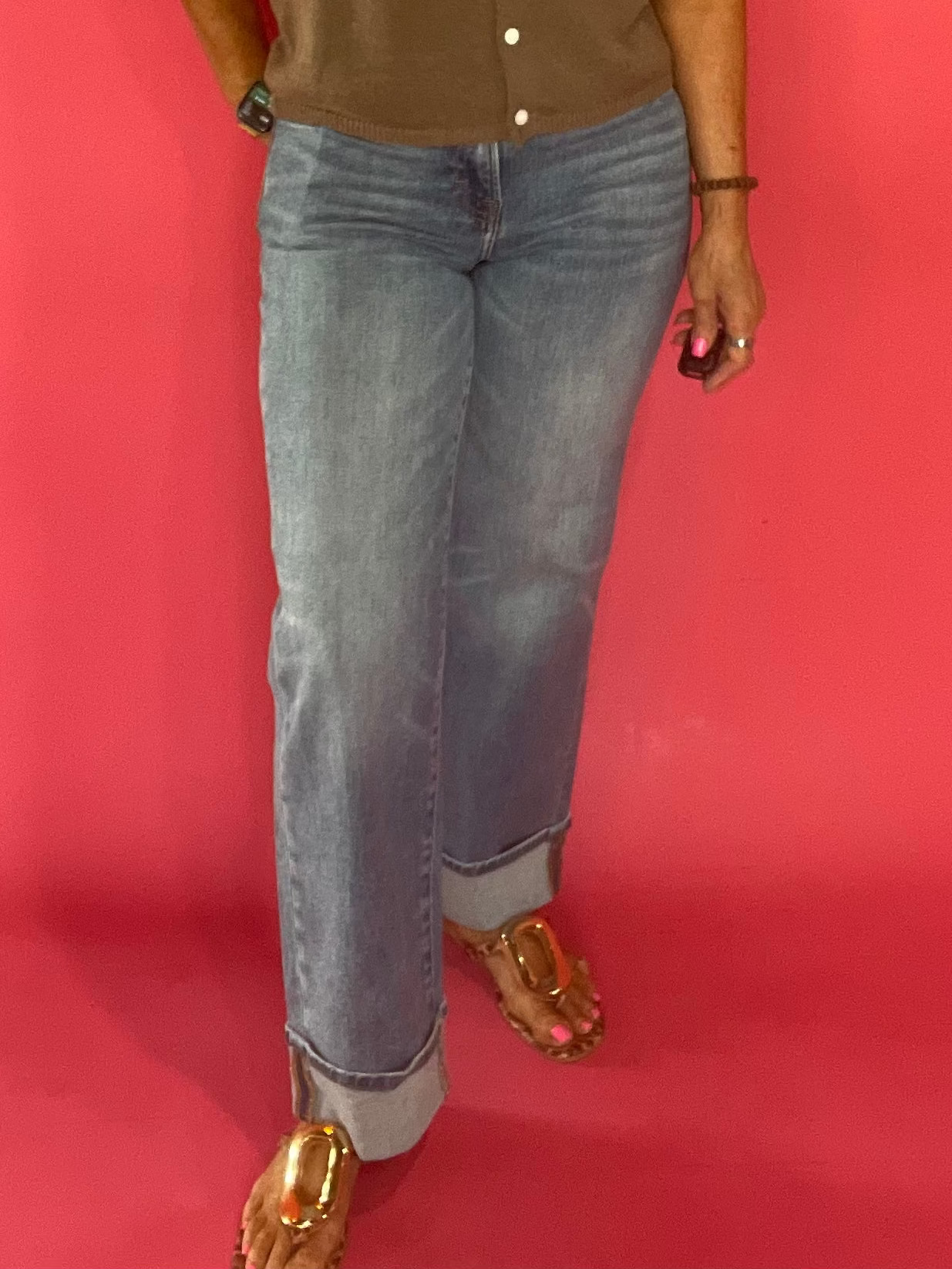 Woman wearing mid rise medium wash cuffed dad jeans with a tucked tee and sneakers