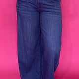 Woman wearing dark wash high rise wide leg trouser jeans with a clean non distressed hem