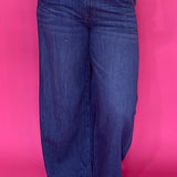 Woman wearing dark wash high rise wide leg trouser jeans with a clean non distressed hem
