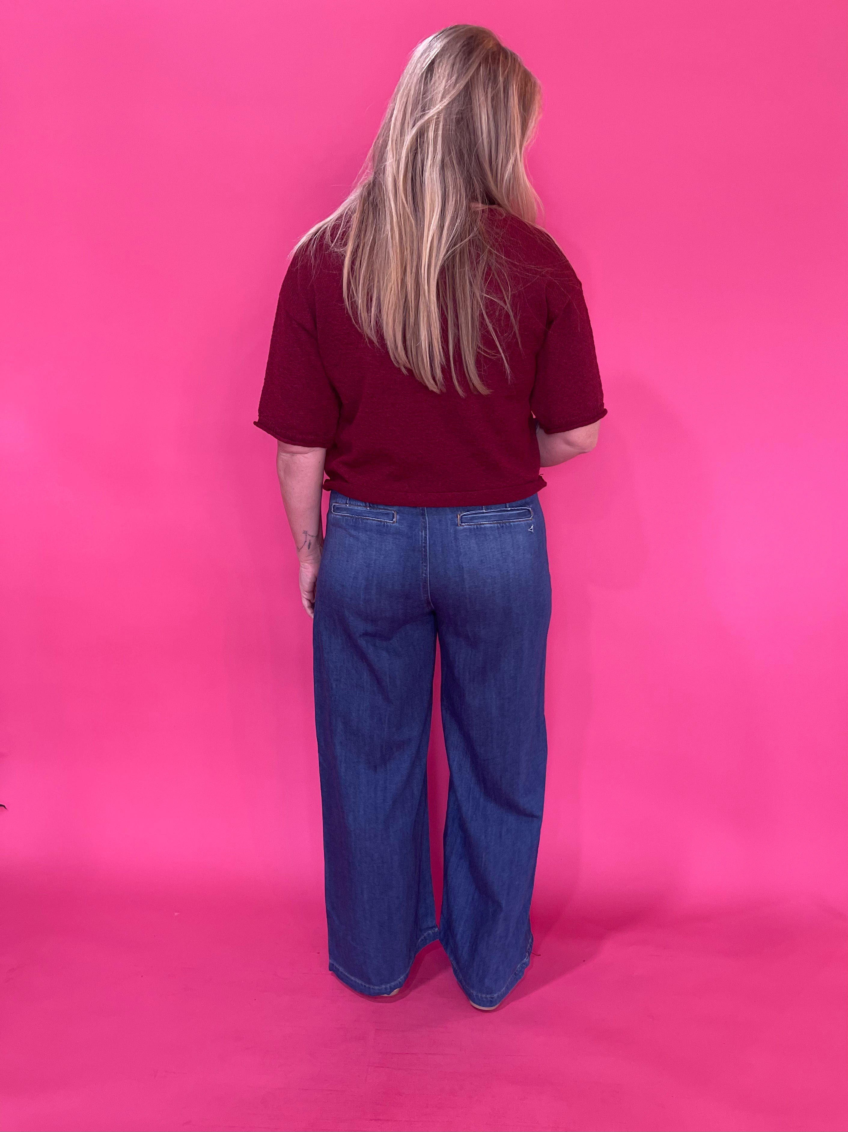 Side view of the high rise dark wash wide leg denim trouser showing the full length leg drape