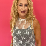 Woman wearing a white floral lace muscle tank over a nude cami with denim shorts