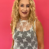 Woman wearing a white floral lace muscle tank over a nude cami with denim shorts