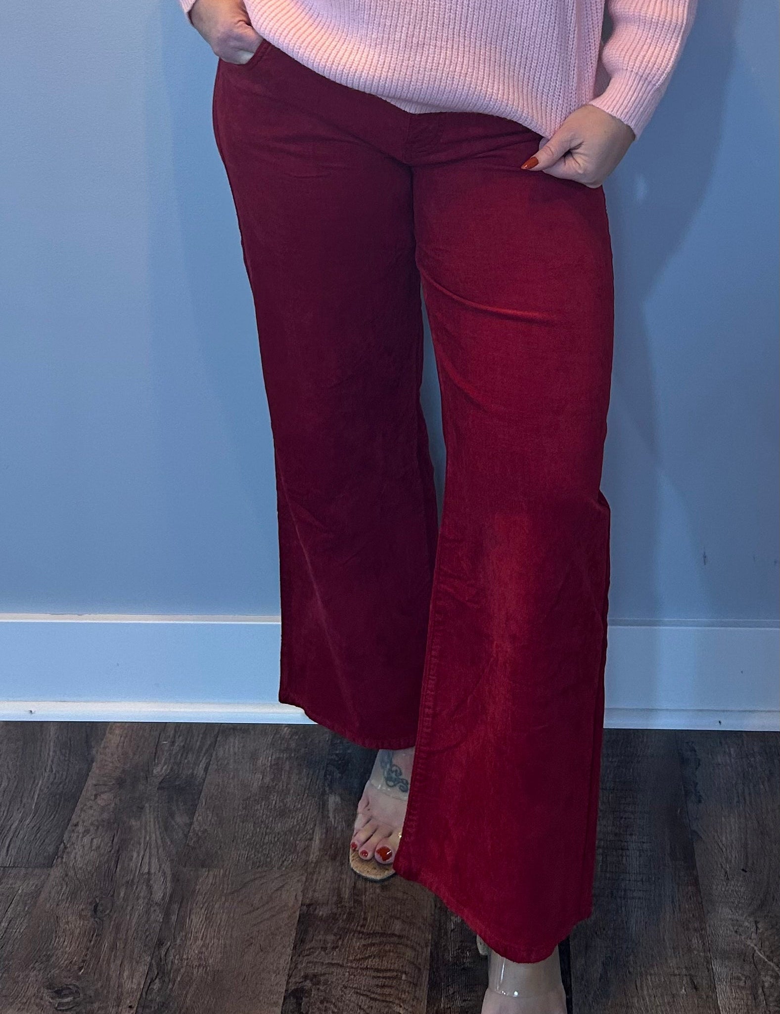 Woman wearing bold red velveteen high rise pants with a wide straight leg and subtle flare