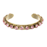 Open antique gold cuff bracelet set with pink crystals, shown worn on a model's wrist