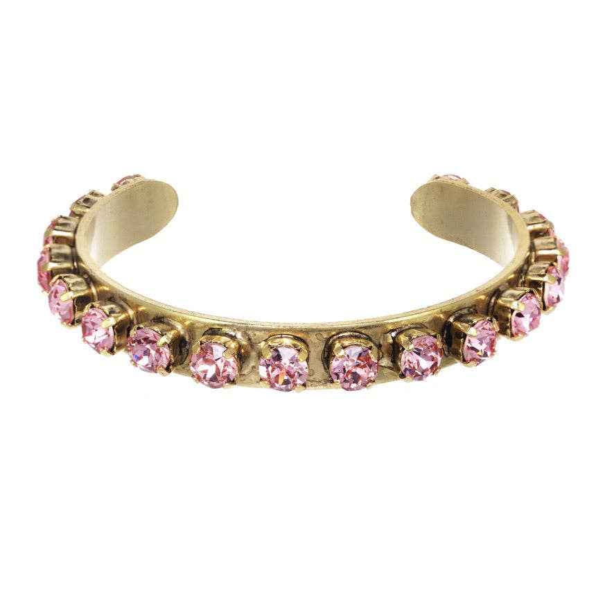 Open antique gold cuff bracelet set with pink crystals, shown worn on a model's wrist