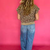 Detail of the solid ribbed hem band at the bottom of the leopard print cap sleeve knit top