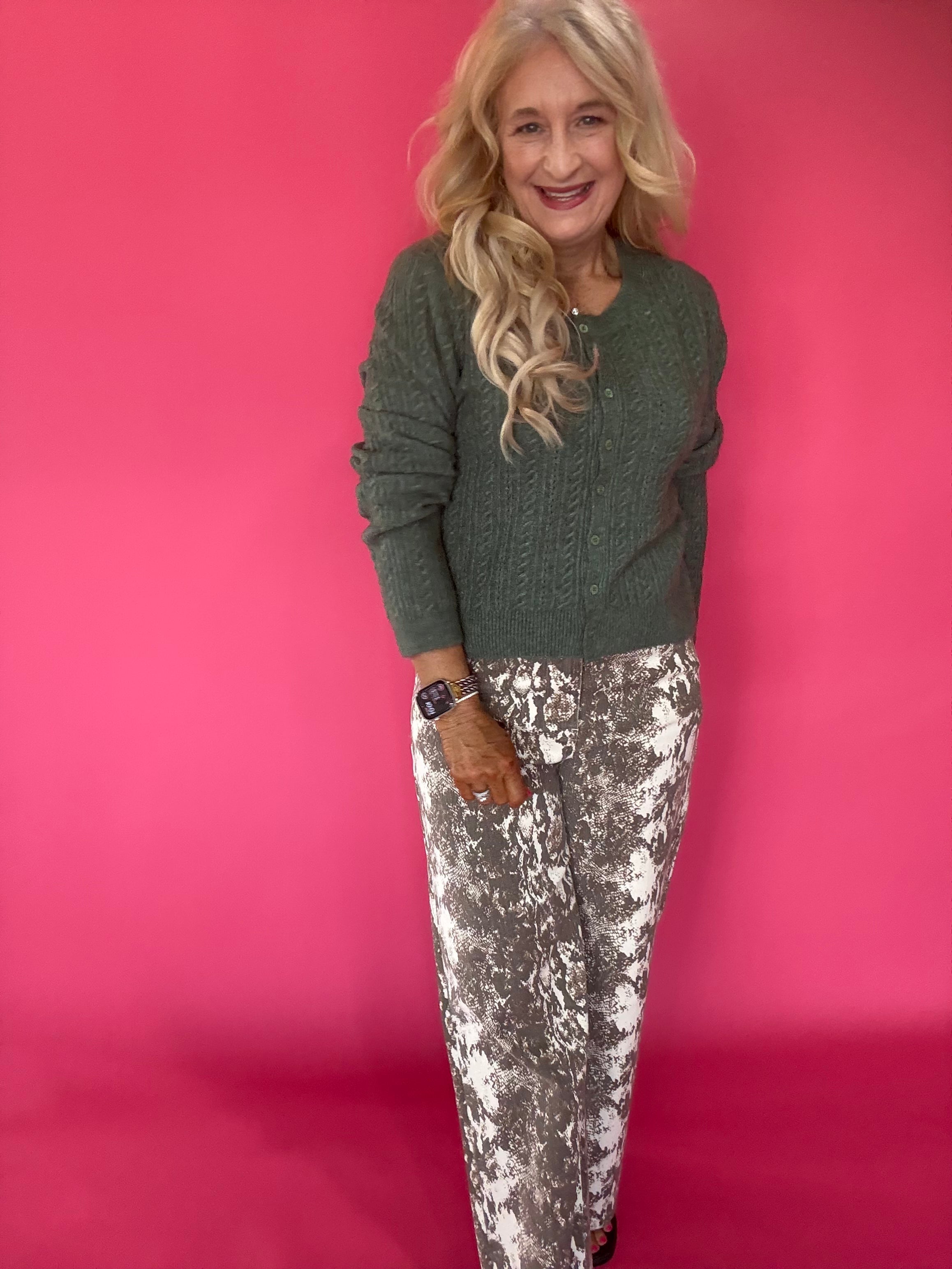 Woman styling the green pointelle cardigan open over a fitted tank and wide-leg trousers