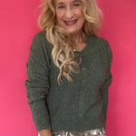 Woman wearing a monstera green pointelle knit button-front cardigan over high-waisted denim