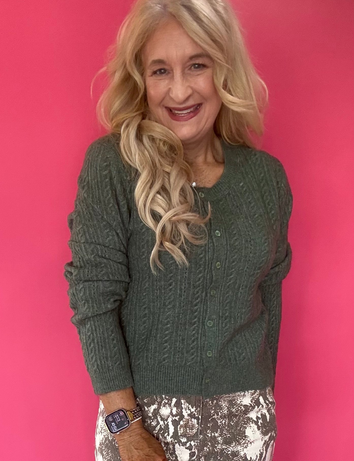 Woman wearing a monstera green pointelle knit button-front cardigan over high-waisted denim