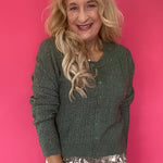 Woman wearing a monstera green pointelle knit button-front cardigan over high-waisted denim