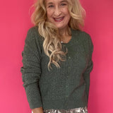 Woman wearing a monstera green pointelle knit button-front cardigan over high-waisted denim