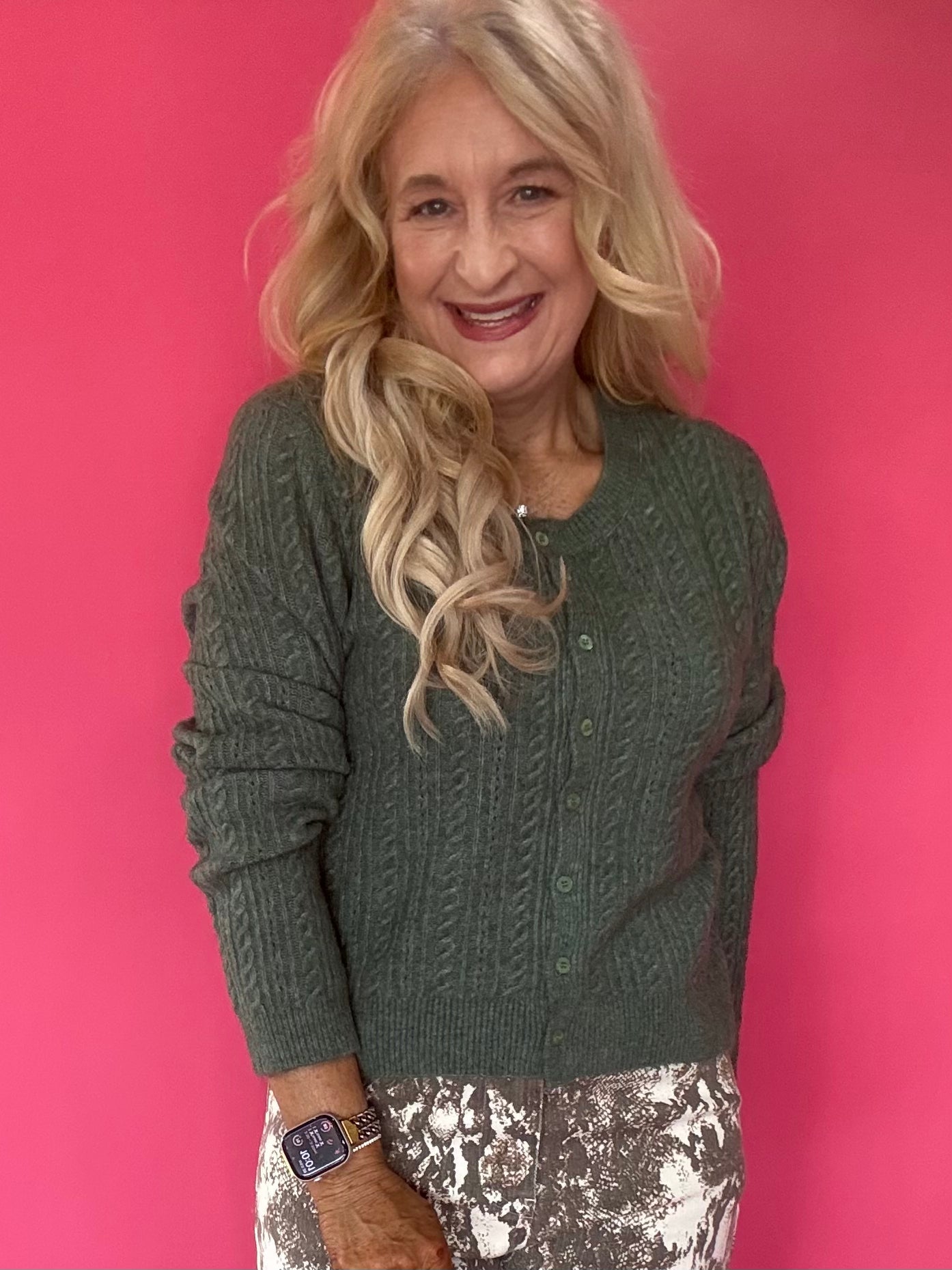 Woman wearing a monstera green pointelle knit button-front cardigan over high-waisted denim