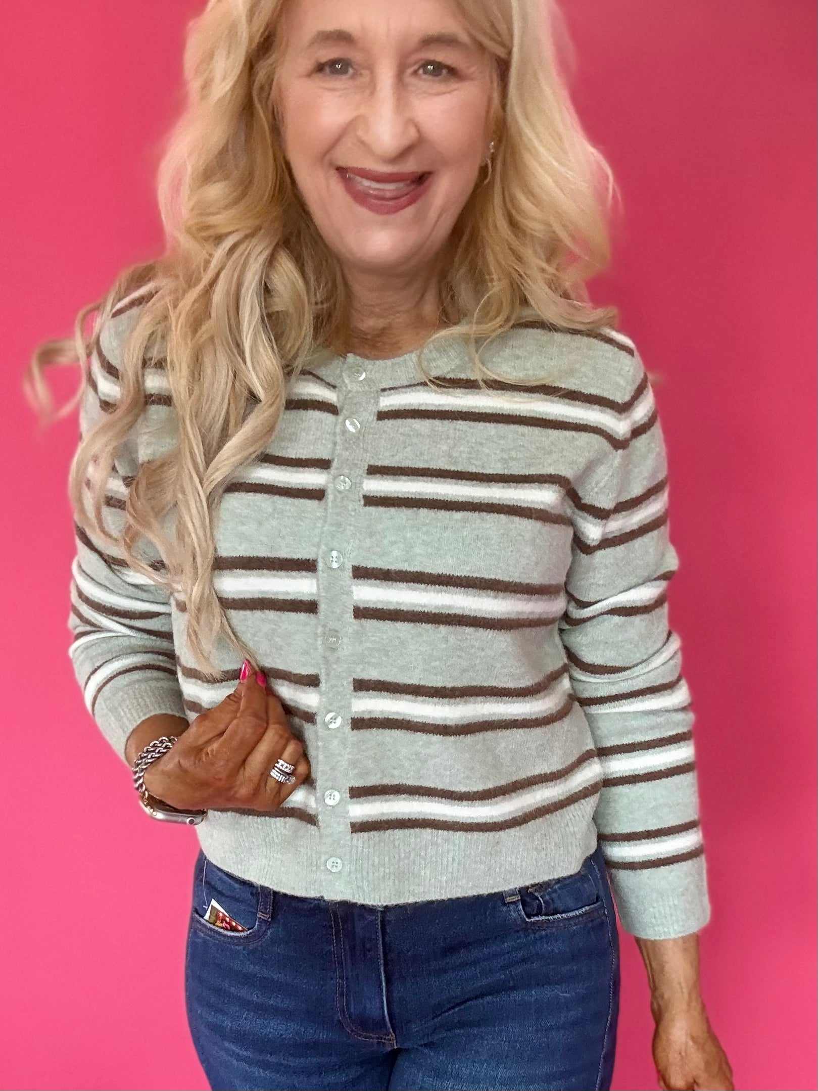 Woman wearing an aqua and cream striped button front cardigan with a crew neckline