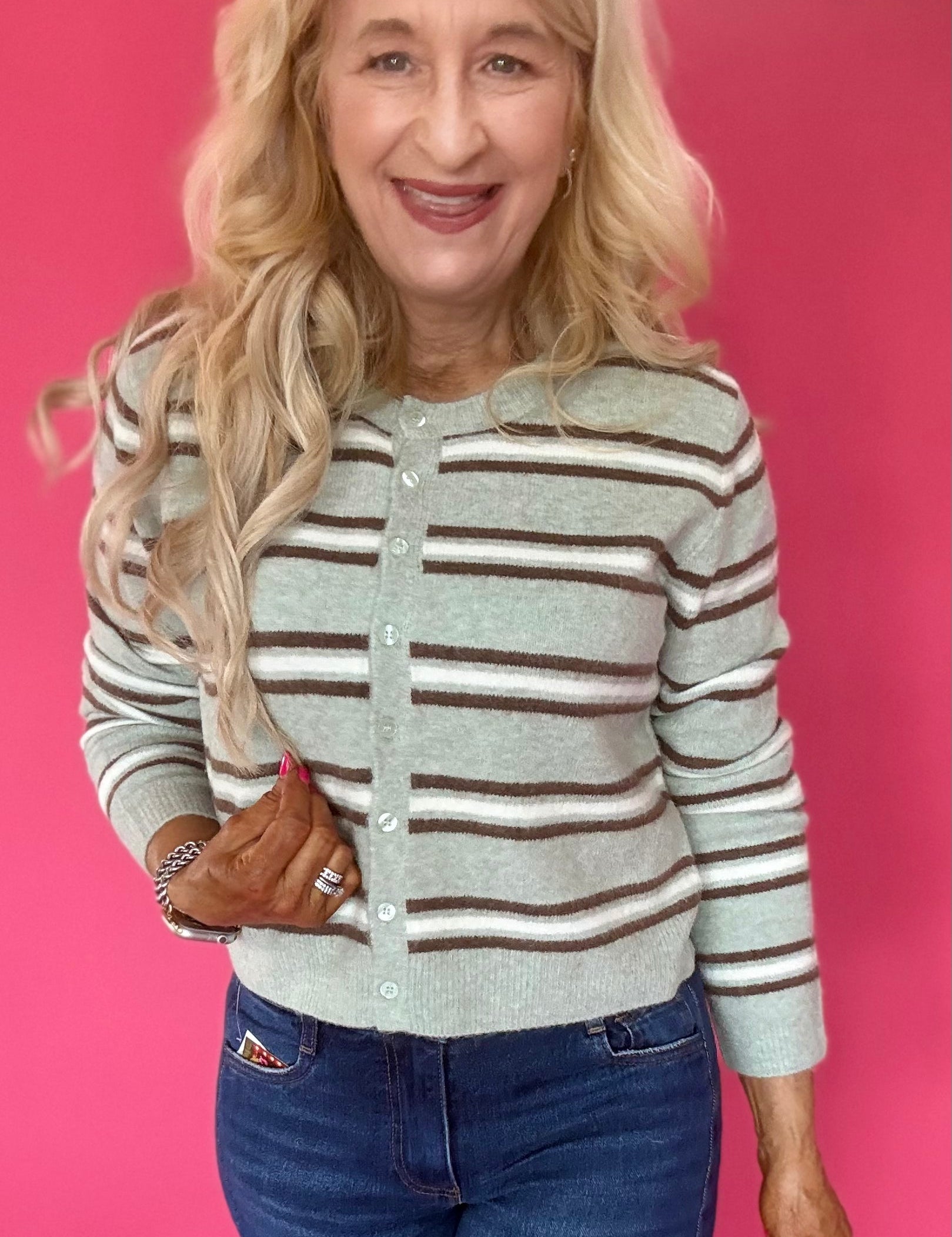Woman wearing an aqua and cream striped button front cardigan with a crew neckline