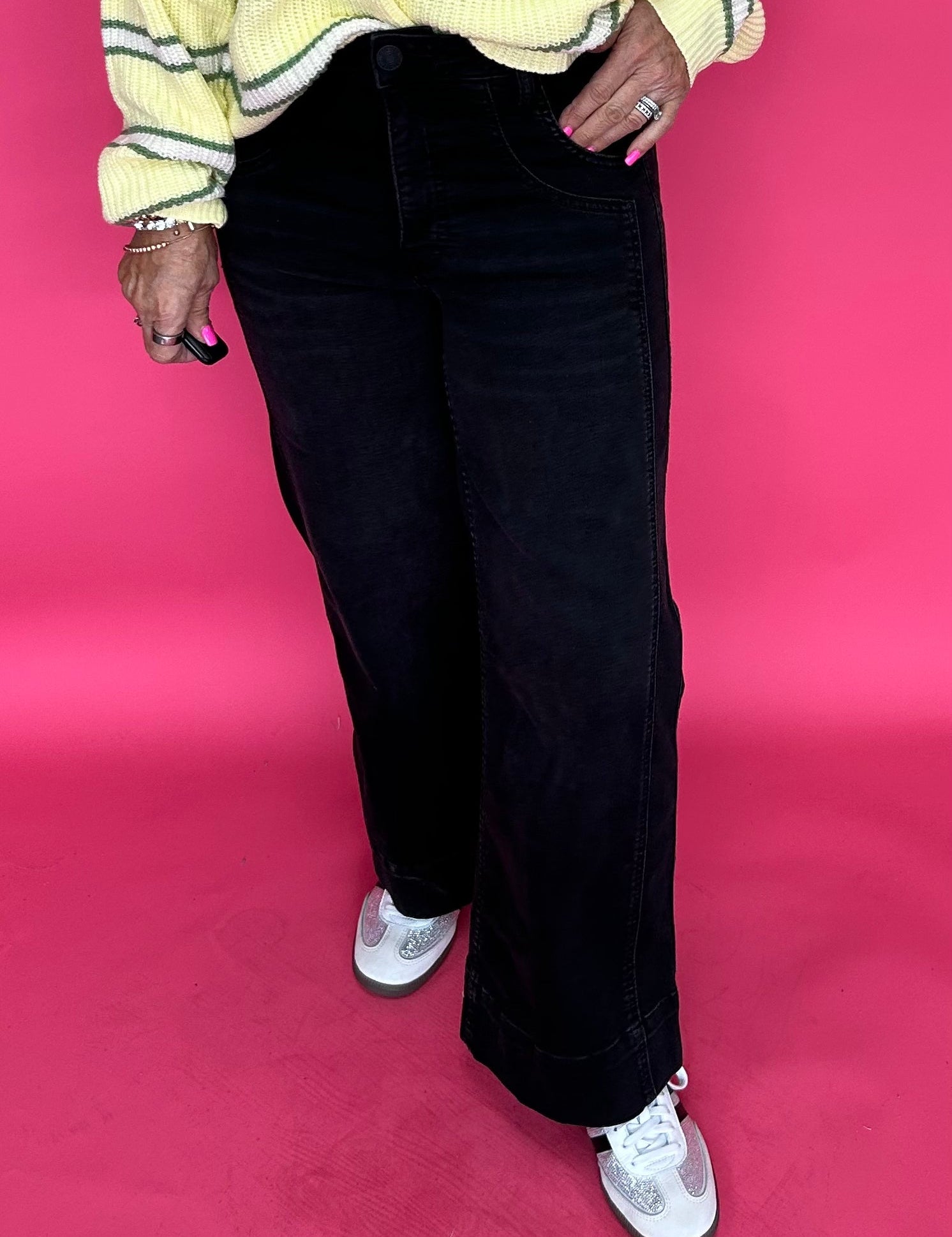 Woman wearing black high rise wide leg jeans with a wide roll up hem and a fitted turtleneck