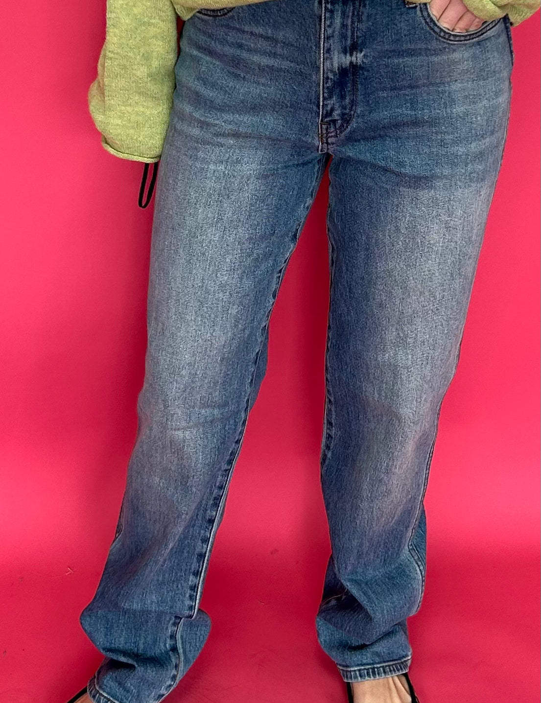 Woman wearing high rise straight leg jeans in a dark determin wash with a tucked sweater