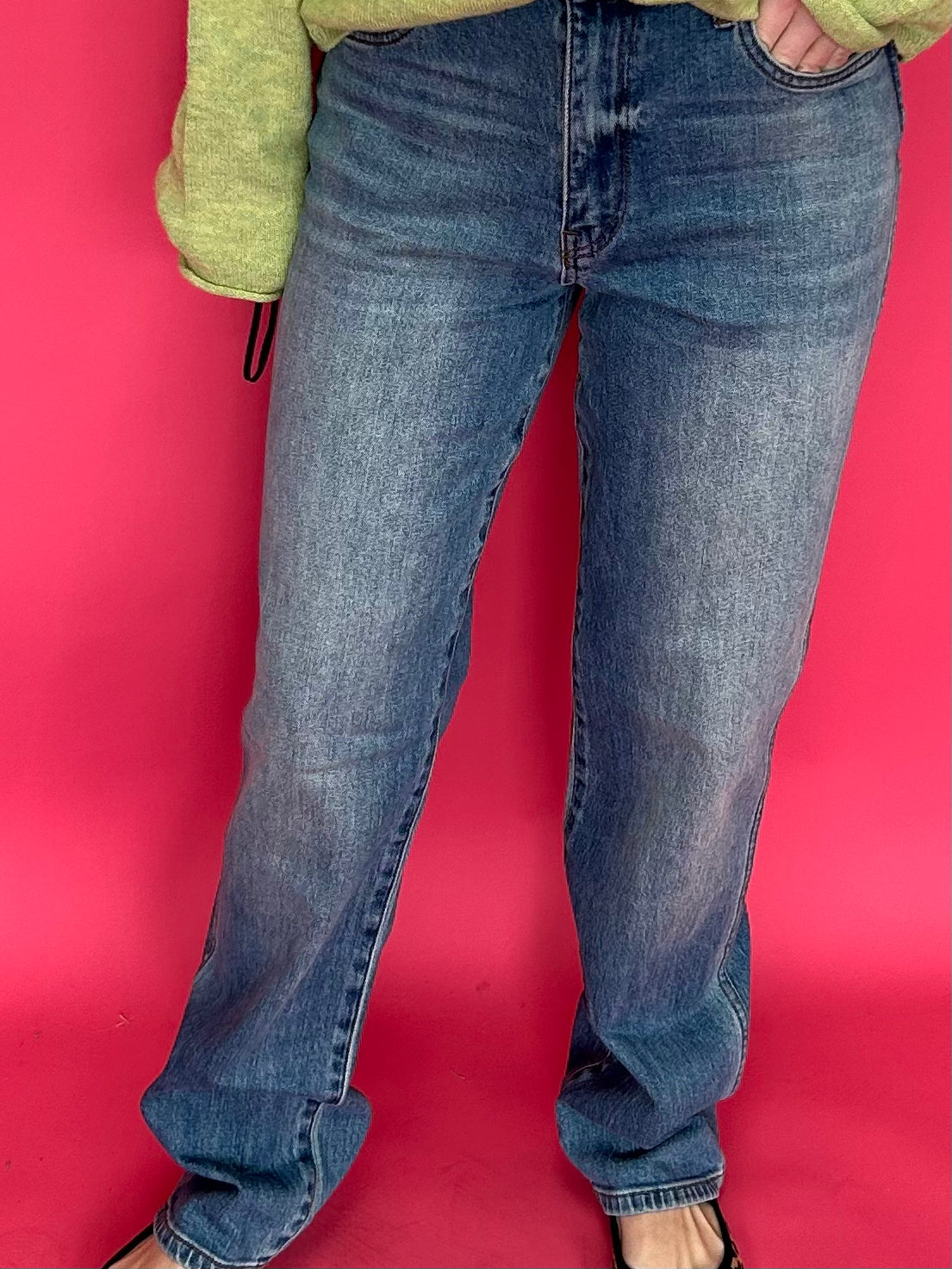 Woman wearing high rise straight leg jeans in a dark determin wash with a tucked sweater