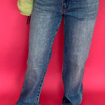 Woman wearing high rise straight leg jeans in a dark determin wash with a tucked sweater