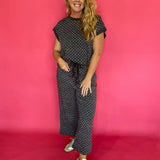 Woman wearing a charcoal micro polka dot scuba lounge set with a cap sleeve top and wide leg pants