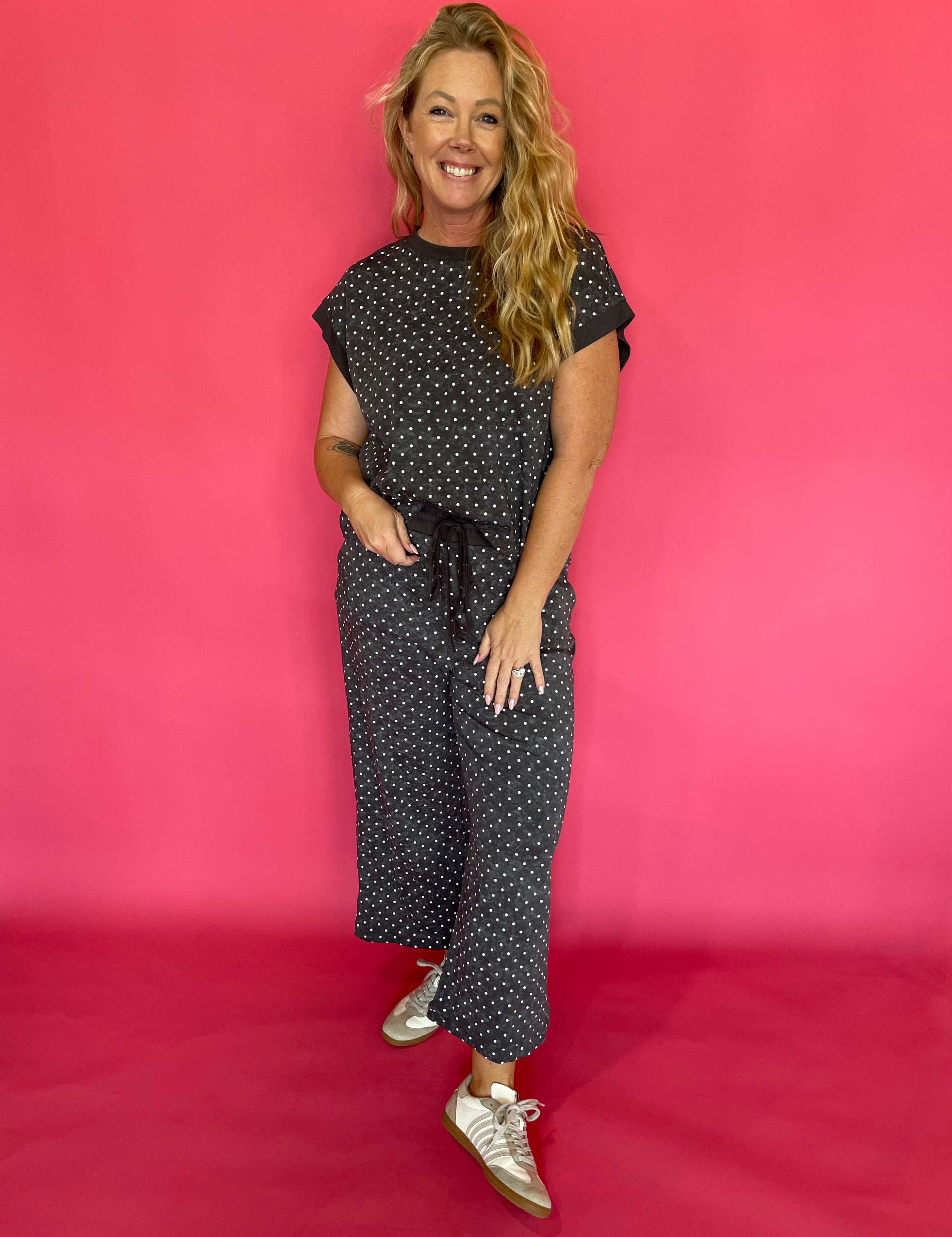 Woman wearing a charcoal micro polka dot scuba lounge set with a cap sleeve top and wide leg pants