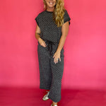 Woman wearing a charcoal micro polka dot scuba lounge set with a cap sleeve top and wide leg pants