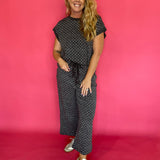 Woman wearing a charcoal micro polka dot scuba lounge set with a cap sleeve top and wide leg pants