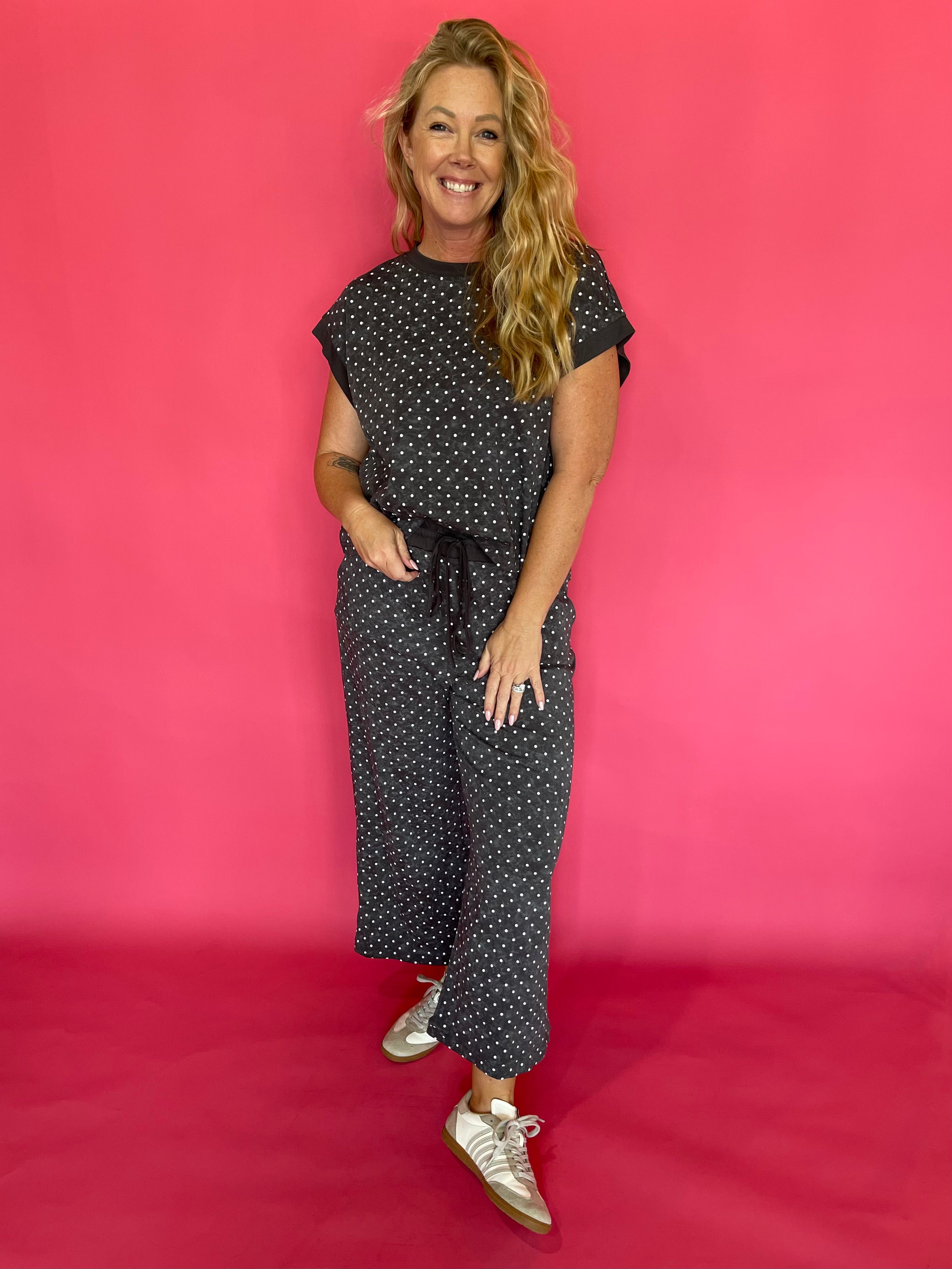 Woman wearing a charcoal micro polka dot scuba lounge set with a cap sleeve top and wide leg pants