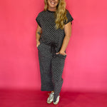 Flat lay of the charcoal micro polka dot cap sleeve top and matching wide leg cropped pants