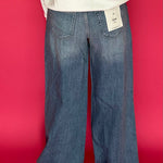 Side view showing the 33 inch inseam and full wide trouser leg in medium wash stretch denim