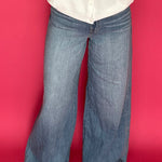 Woman wearing medium wash wide leg trouser jeans with a high rise waist and a tucked top