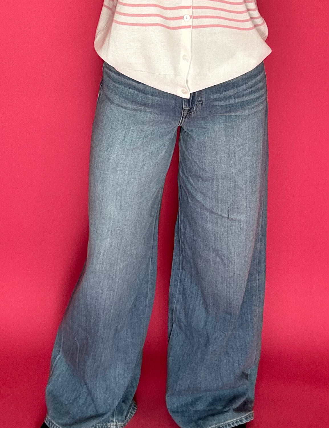 Woman wearing medium wash wide leg trouser jeans with a high rise waist and a tucked top