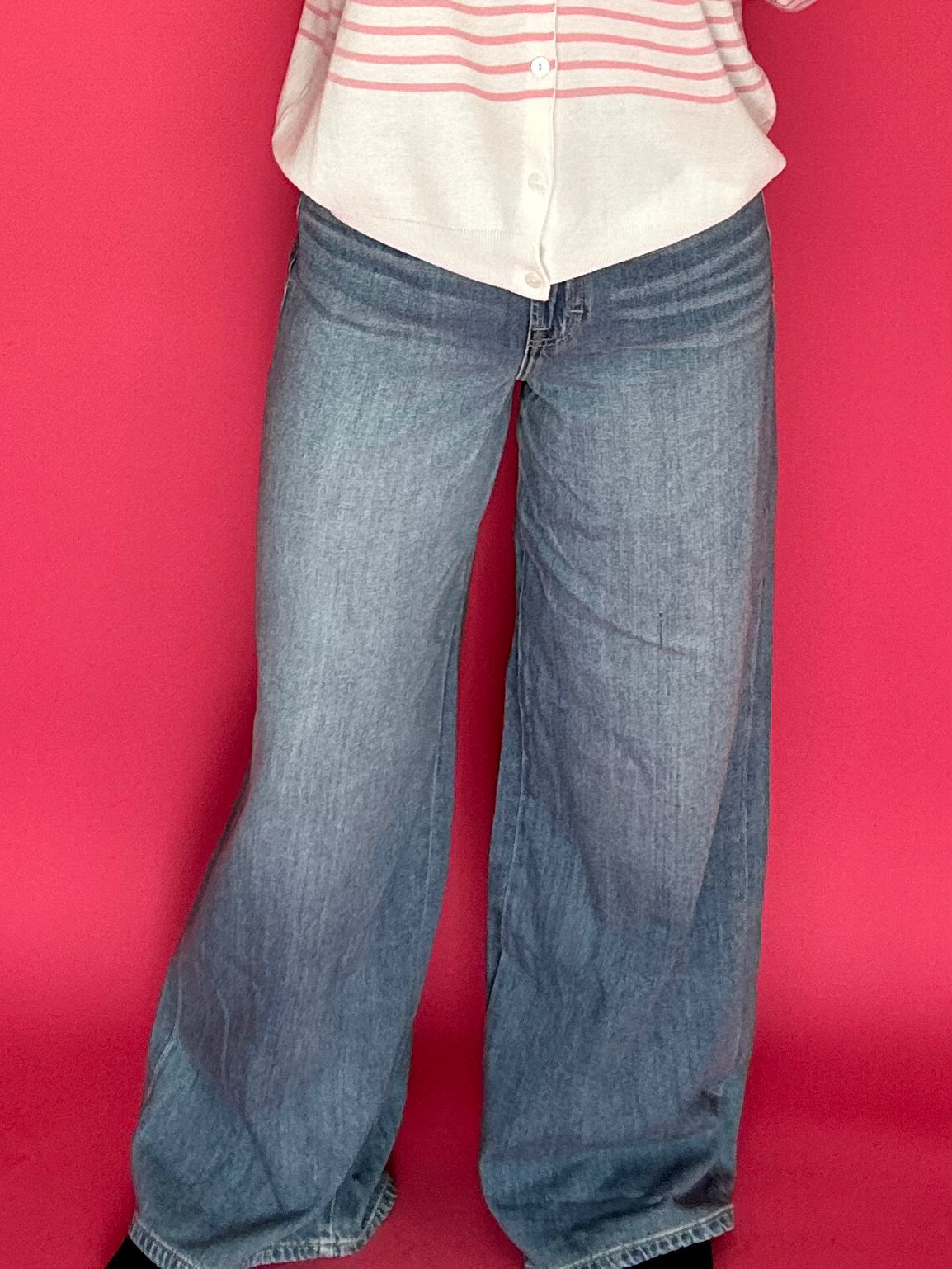 Woman wearing medium wash wide leg trouser jeans with a high rise waist and a tucked top