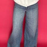 Woman wearing medium wash wide leg trouser jeans with a high rise waist and a tucked top