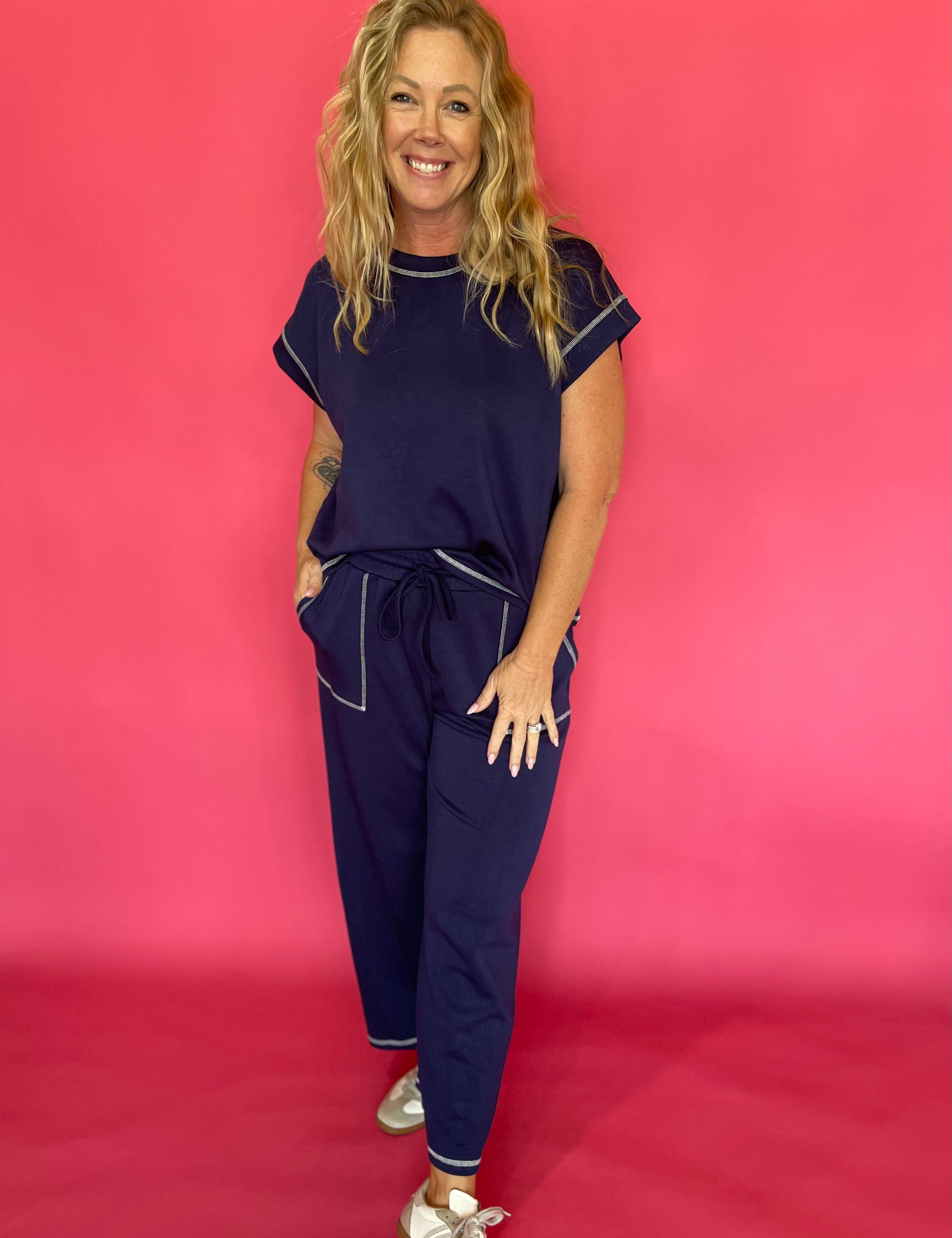 Woman wearing a navy scuba lounge set with a cap sleeve top and wide leg drawstring pants