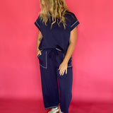 Close-up of the contrast stitching and crew neckline on the navy scuba cap sleeve top