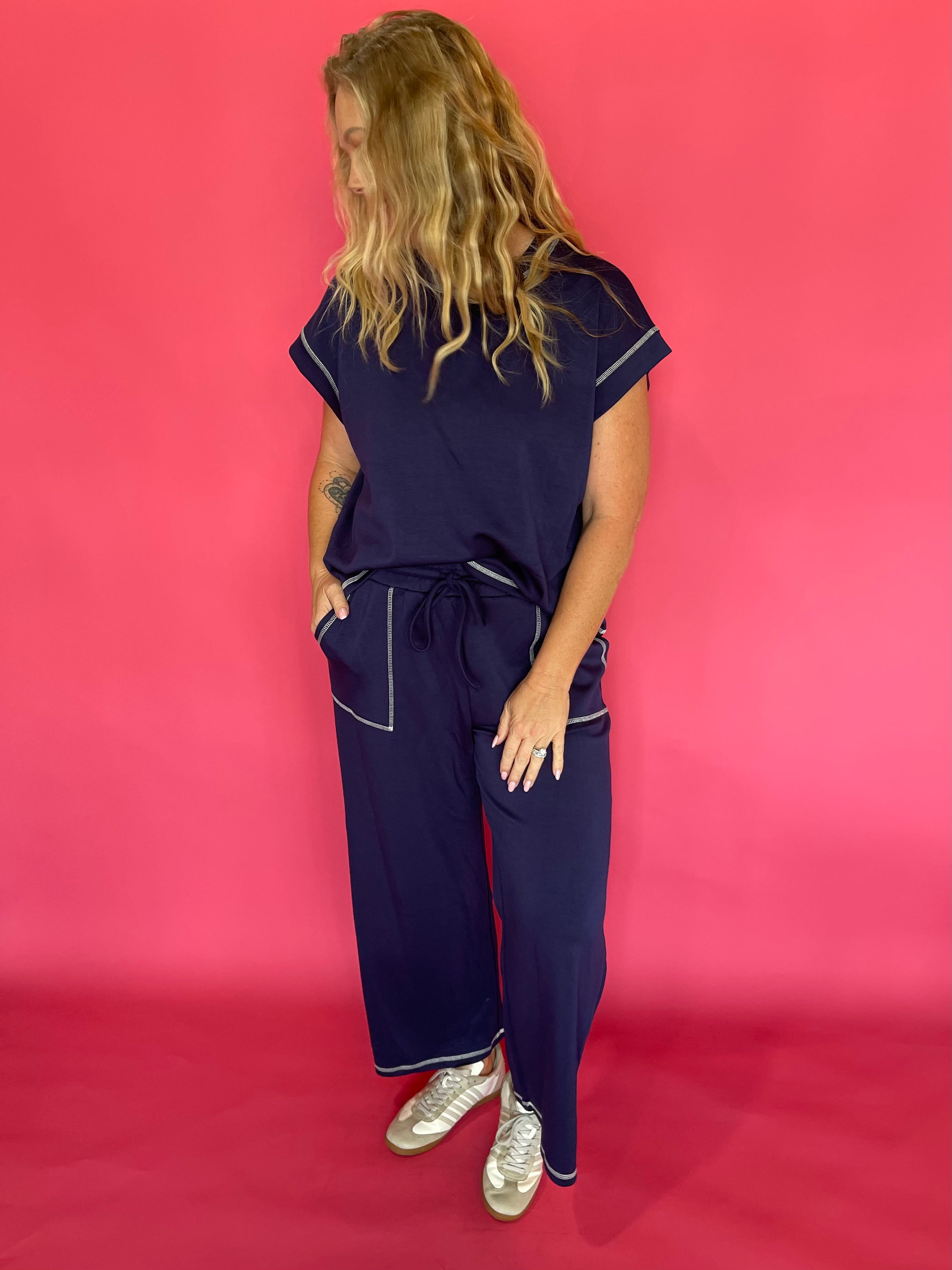 Close-up of the contrast stitching and crew neckline on the navy scuba cap sleeve top