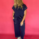 Close-up of the contrast stitching and crew neckline on the navy scuba cap sleeve top