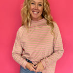 Woman wearing an oversized yarn-dyed striped mock neck long sleeve tee over straight leg denim and sneakers