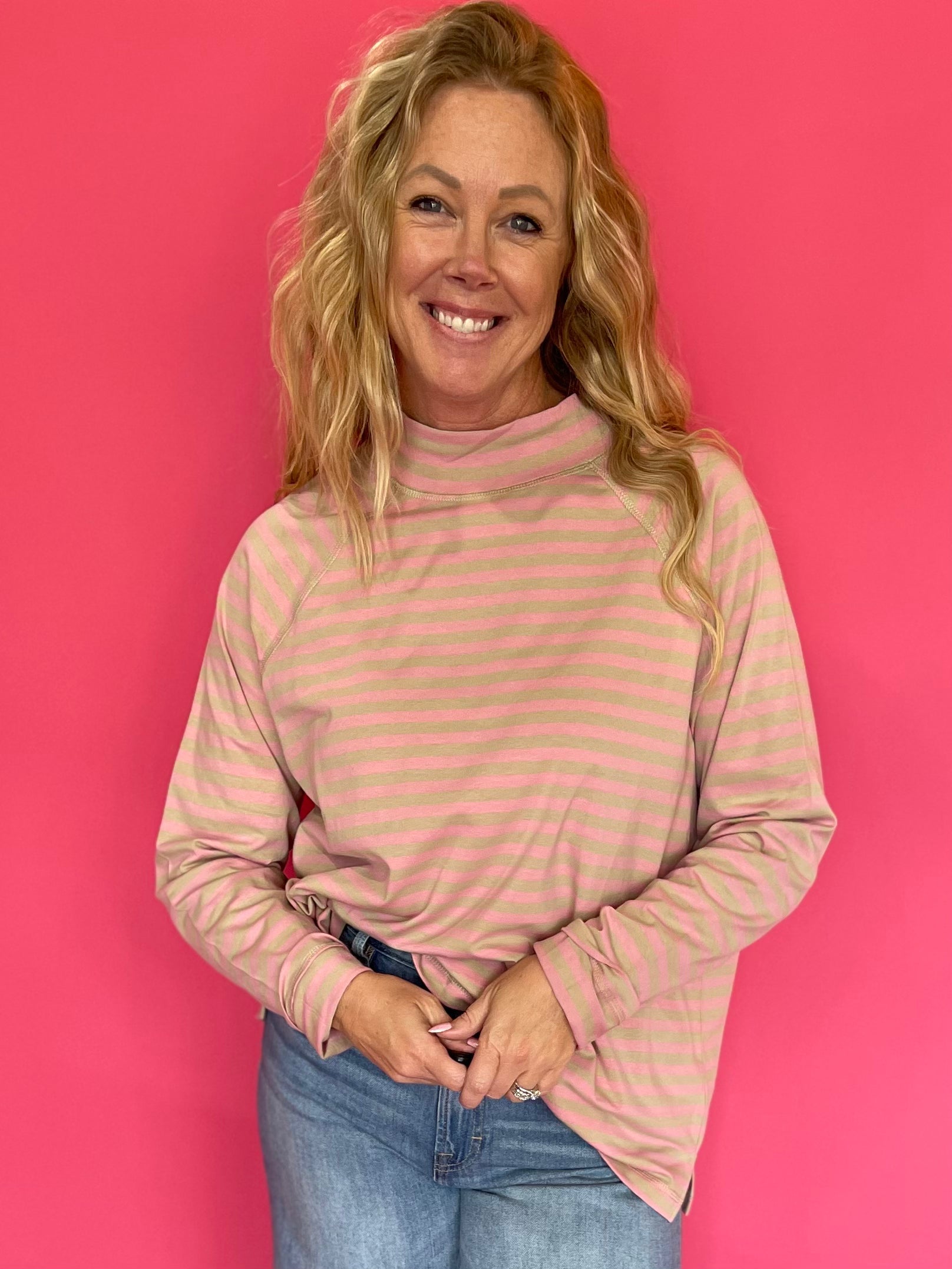 Woman wearing an oversized yarn-dyed striped mock neck long sleeve tee over straight leg denim and sneakers
