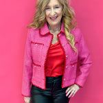 Woman wearing a fuchsia pink tweed jacket with contrast embroidered trim and a spread collar