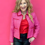 Woman wearing a fuchsia pink tweed jacket with contrast embroidered trim and a spread collar